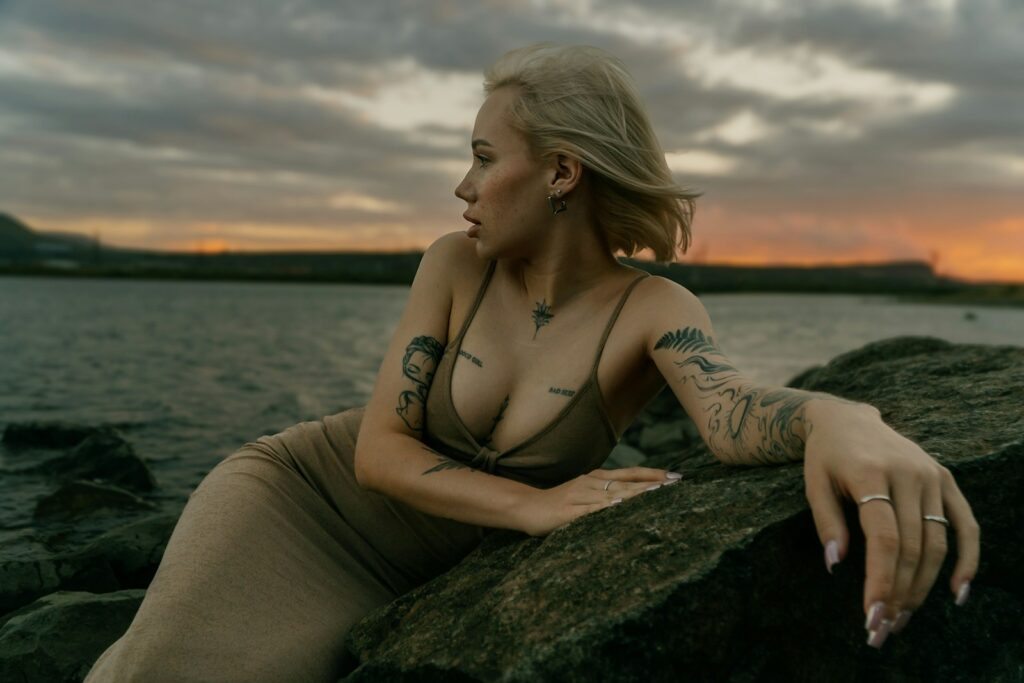 A woman sitting on a rock next to a body of water