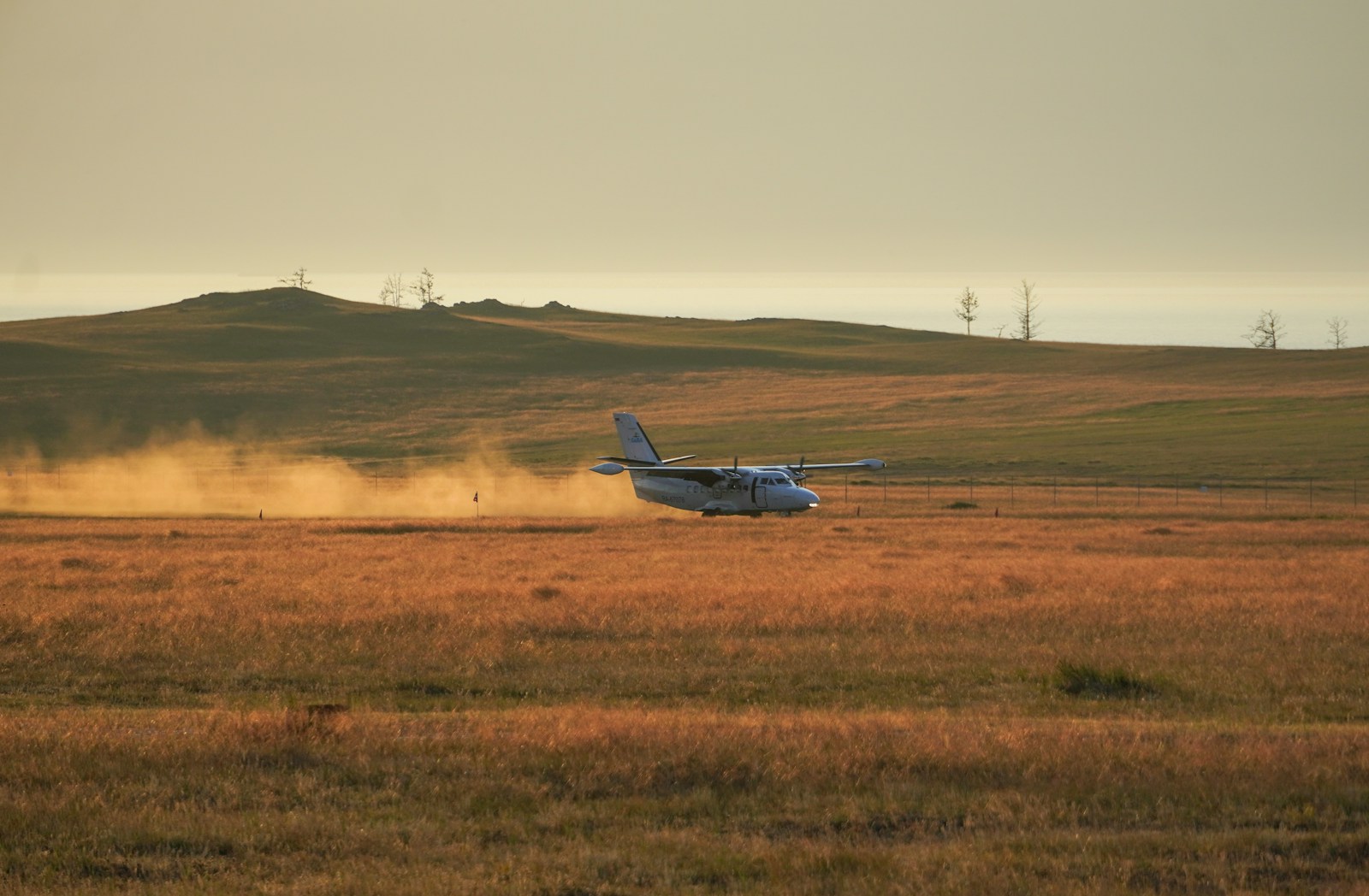 A small plane landing in a field with a hill in the background